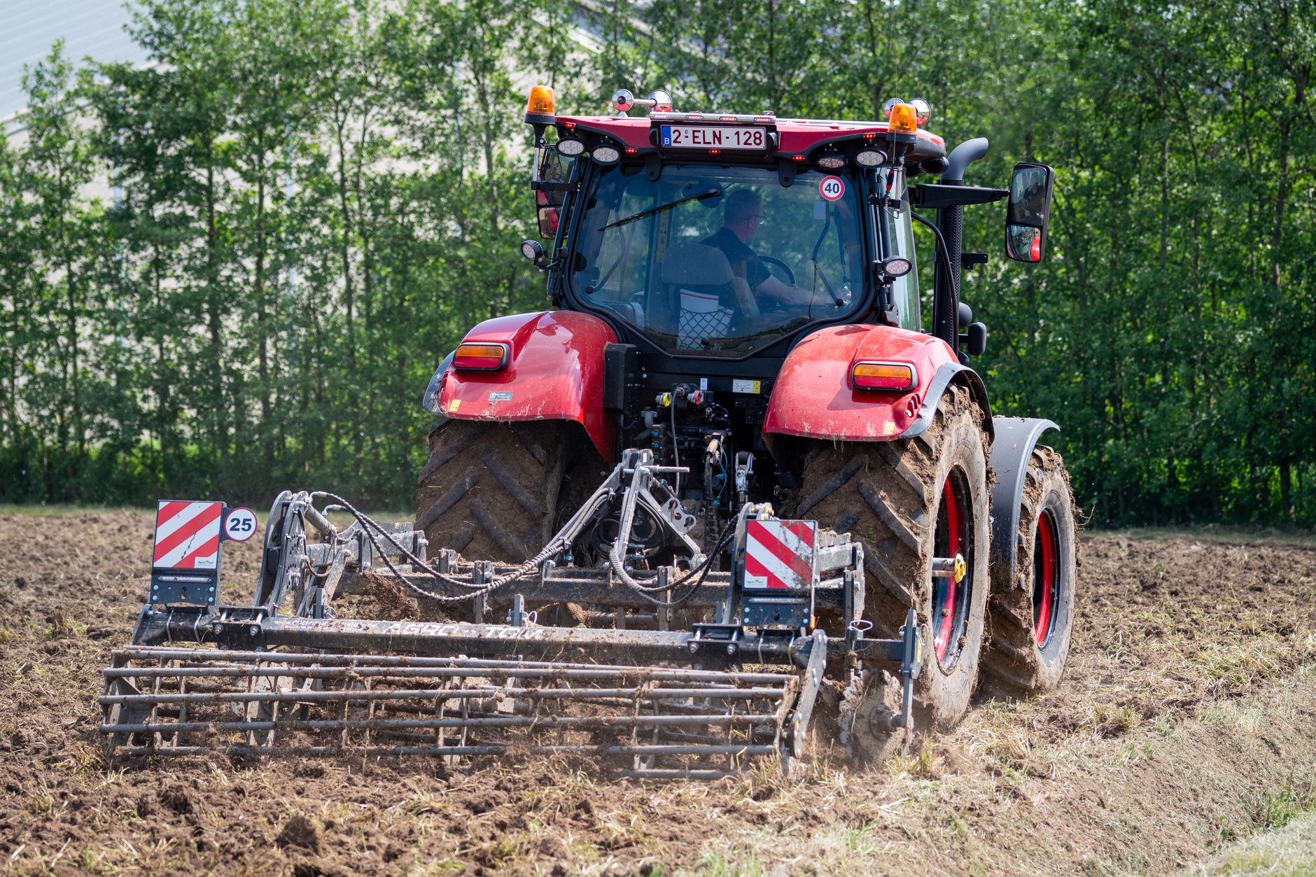 Petit tracteur rouge qui travaille la terre d'un champ