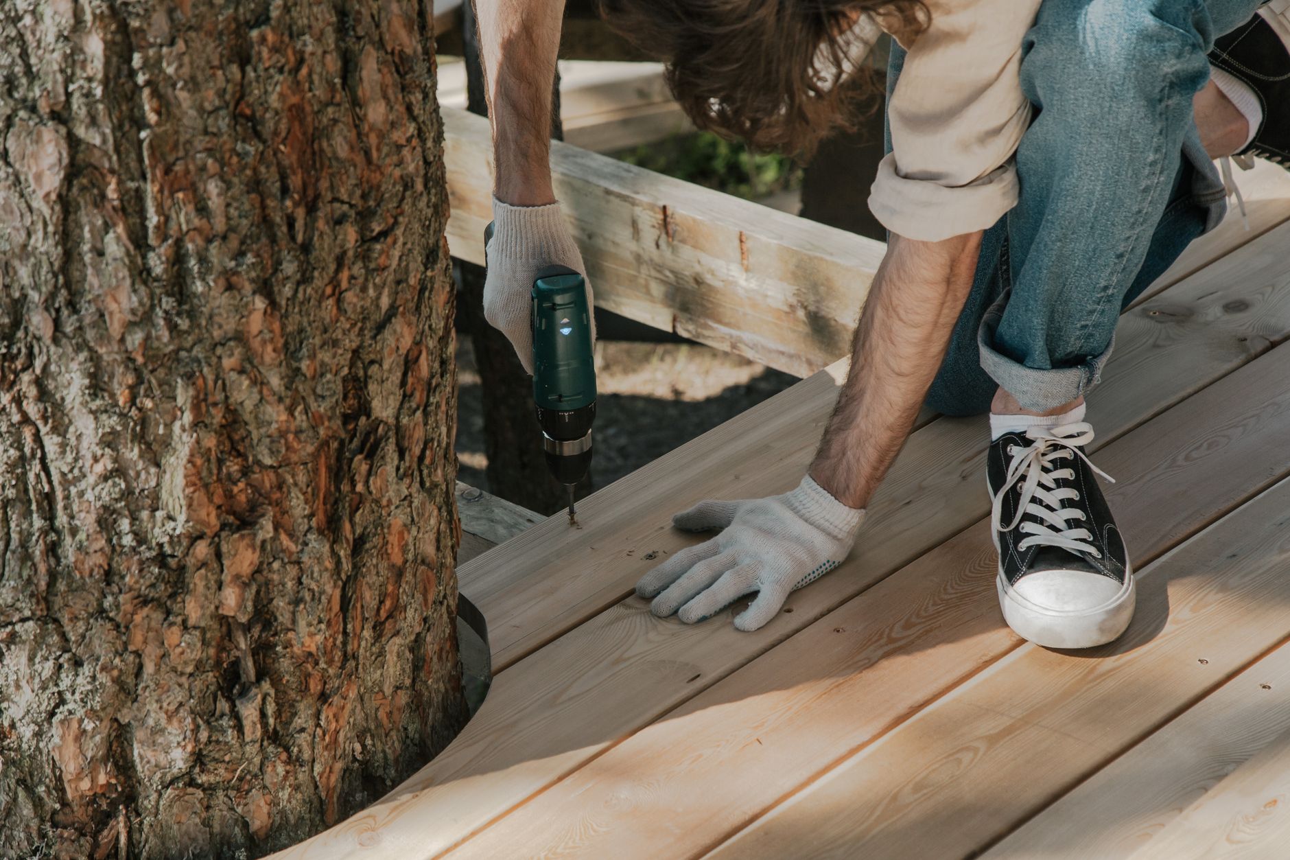 Ouvrier qui visse des planches en bois à la perceuse